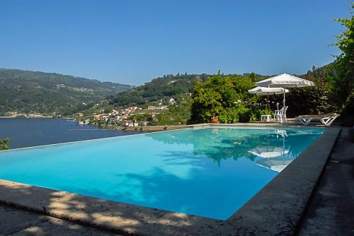 une grande piscine bleue à côté d'un lac dans l'établissement Casa da Torre, Porto Manso, à Ribadouro
