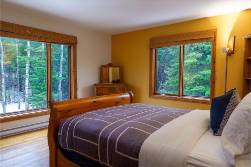 a bedroom with a bed and two large windows at La Romane Val-david Spa & Pool in Val-David