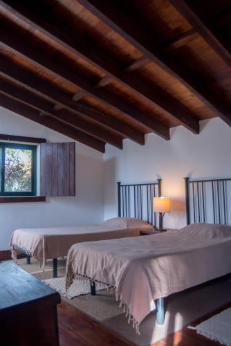 two beds in a room with wooden ceilings at Casa da Torre, Porto Manso in Riba Douro
