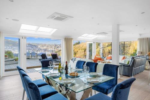 a dining room with a table and blue chairs at Homefield - Chic charm with unrivalled river views in Kingswear