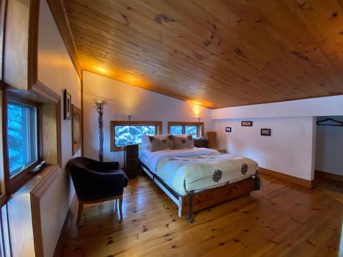 a bedroom with a bed and a wooden ceiling at Le Sculptural Exitchalets Laurentides Spa in Val-David