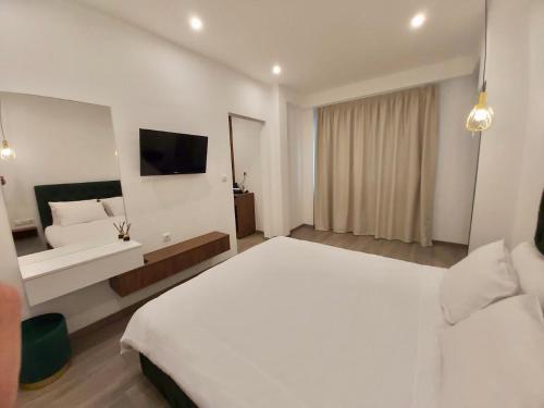 a hotel room with a white bed and a television at Real City Suites Syntagma in Athens
