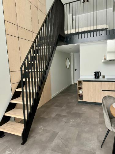 a staircase leading up to a kitchen and a living room at Albatross Loft in Ķesterciems
