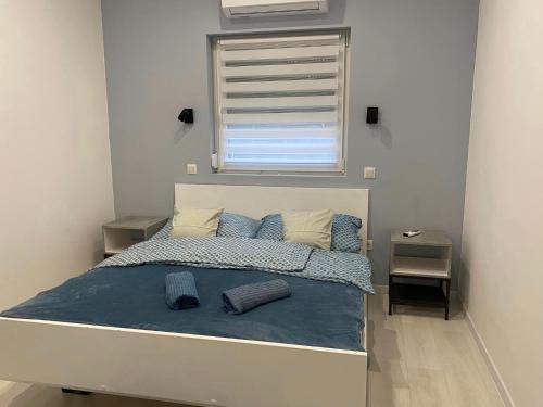 a bedroom with a bed with blue sheets and a window at LURKÓ Apartmanok Siófok in Siófok