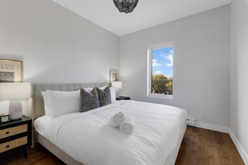 a bedroom with a large white bed with a window at Lofts de la petite Italie in Montréal