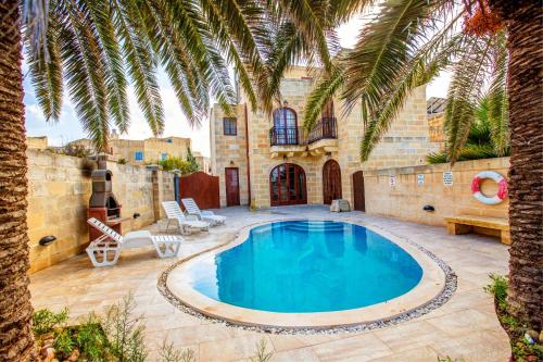 - une piscine dans une cour avec un palmier dans l'établissement 5 Bedroom Farmhouse with Private Pool & Views, à L-Għarb
