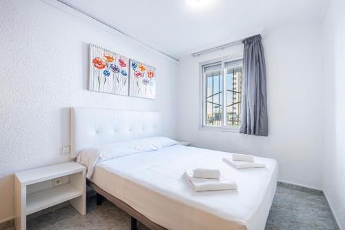 a white bedroom with a bed and a window at Edimar 2-3 Apartment Levante Beach in Benidorm