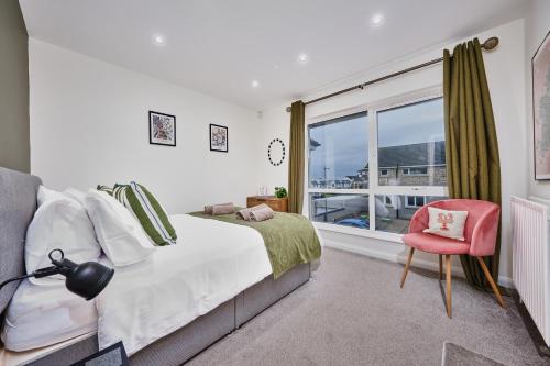 ein Schlafzimmer mit einem Bett, einem Fenster und einem Stuhl in der Unterkunft Portstewart Central Loft Apartment in Portstewart