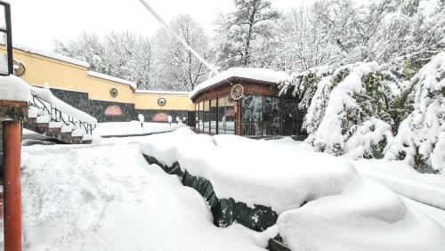 een tuin bedekt met sneeuw met een gebouw op de achtergrond bij Маришки дол in Raduil