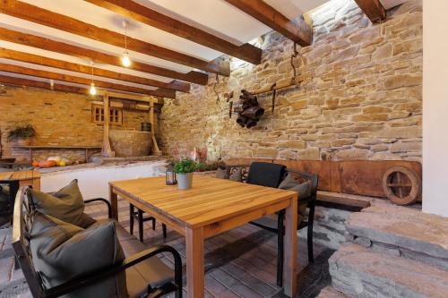 een eetkamer met een houten tafel en een stenen muur bij Viscri 44 in Viscri
