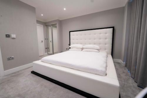 Luxury, Modern & Cosy 1 Bedroom Prestige London Apartment في لندن: غرفة نوم بيضاء مع سرير أبيض كبير