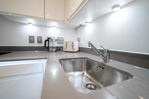 uma cozinha com um lavatório e uma bancada em Luxury, Modern & Cosy 1 Bedroom Prestige London Apartment em Londres