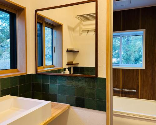 La salle de bains est pourvue d'une baignoire, d'un lavabo et d'un miroir. dans l'établissement Hakuba Bliss Cottage - Vacation STAY 28524v, à Hakuba