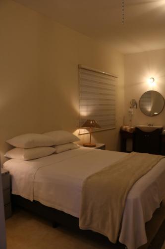 a bedroom with a white bed with a lamp and a desk at Casa Bugambilias in Todos Santos
