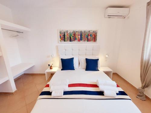 a bedroom with a large white bed with blue pillows at Branco Sea Holiday Apartments in Santa Maria
