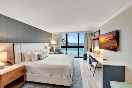 Tideline Palm Beach Ocean Resort and Spa في بالم بيتش: غرفة فندق بسرير كبير ومكتب ومكتب