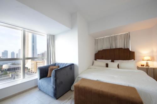 sypialnia z dużym łóżkiem i niebieskim krzesłem w obiekcie Sunny Seaside 2 Bedroom Apartment, Dubai Marina w Dubaju