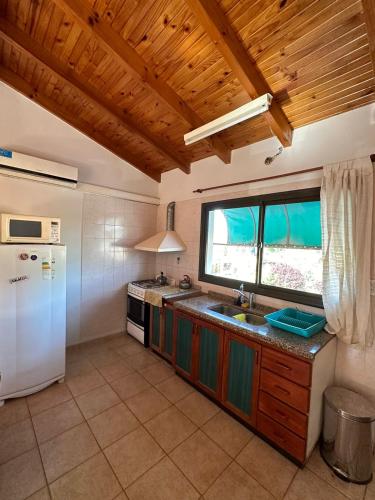 a kitchen with a white refrigerator and a window at Departamento Céntrico Estilo Centroeuropeo - FEPANGUS in Villa General Belgrano