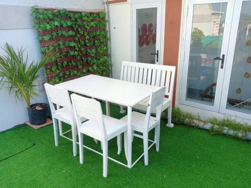 una mesa blanca y sillas en un patio con césped en Nhà bốn chín en Ấp Khánh Phước (1)