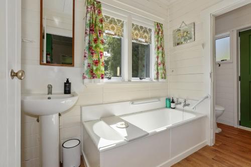 Baño blanco con bañera y lavamanos en Okareka Lakefront, en Rotorua
