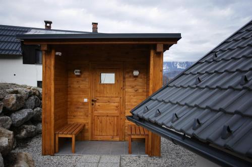 eine Holzhütte mit einer Holztür und einer Bank in der Unterkunft MY TIME Holiday House with sauna in Zgornje Gorje