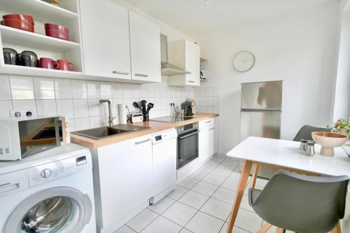 - une cuisine blanche avec un lave-linge et une table dans l'établissement Design Apartment - Boxspringbett - Waschmaschine - 55 Zoll Smart-TV - Netflix inklusive - Arbeitsplatz, à Magdebourg