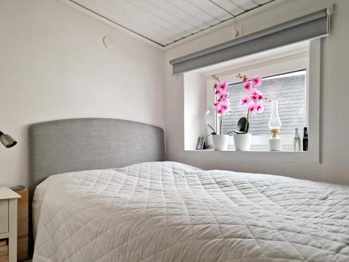 een slaapkamer met een bed en een raam met roze bloemen bij Holiday home SKÖVDE in Skövde