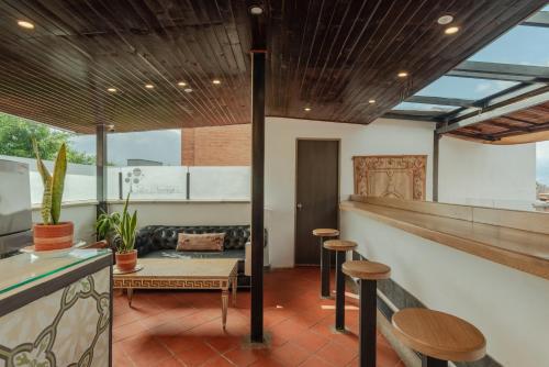 a patio with a bar with stools and a table at Casa Los Naranjos Hostal in Medellín