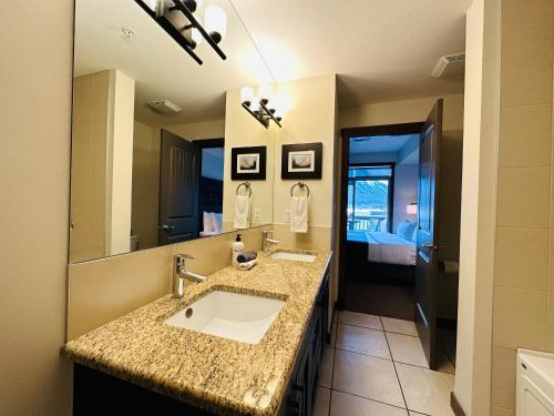 a bathroom with a sink and a large mirror at Canmore Mountain Retreat - Heated Pool & Hot-tub in Canmore