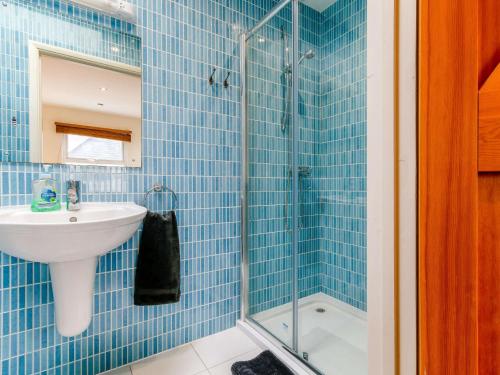 uma casa de banho em azulejos azuis com um lavatório e um chuveiro em 2 Bed in Gurnard 73374 em Gurnard