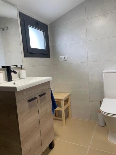 a bathroom with a sink and a toilet and a window at Luminoso dúplex con parking in Terrassa