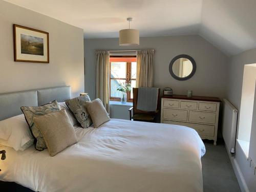 a bedroom with a large white bed and a desk at Mill Pond Cottage in Taunton