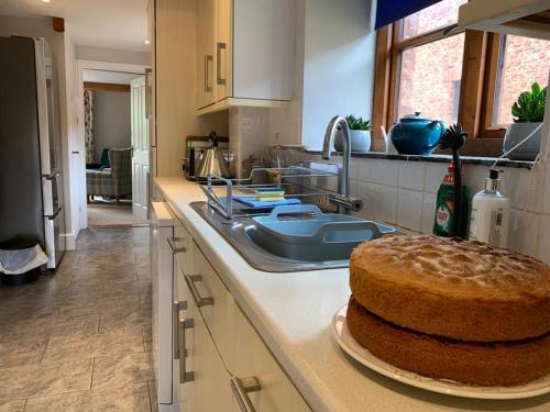 a kitchen counter with a cake on a plate at Mill Pond Cottage in Taunton