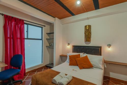 a bedroom with a bed with orange pillows and a window at Casa Los Naranjos Hostal in Medellín