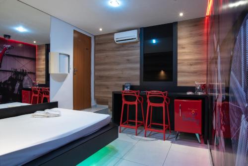 um quarto com uma cama e dois bancos de bar vermelhos em Motel Fantasy 1 em Belo Horizonte