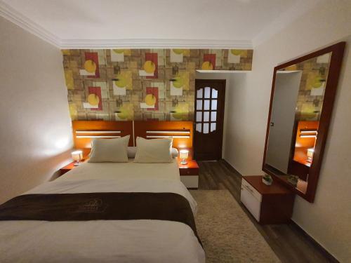 1 dormitorio con 1 cama grande y espejo en YOUVALA Serviced Apartments City Star, en Seis de Octubre