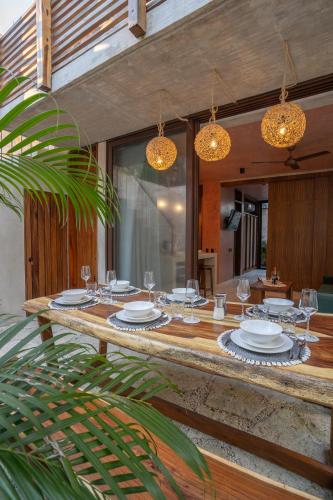 a wooden table with glasses and plates on it at Entorno Tulum - Luxury Villas in Tulum
