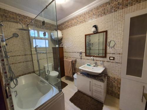 y baño con bañera, lavamanos y ducha. en YOUVALA Serviced Apartments City Star, en Seis de Octubre