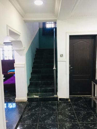 un pasillo con una escalera y una puerta negra en D Light Hotel, en Abuja