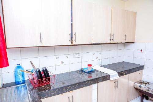 cocina con armarios blancos y encimera en Genesis Executive mlimani en Kisumu