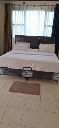 uma cama grande com uma estrutura de madeira num quarto em Genesis Executive mlimani em Kisumu