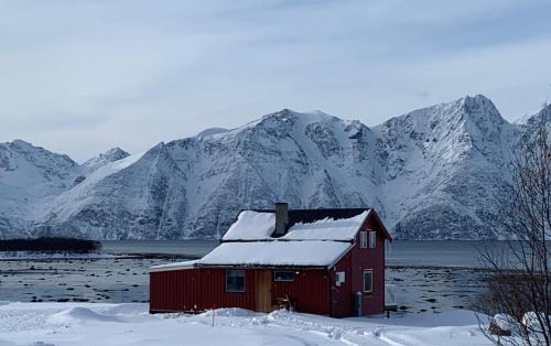 a red house in front of a snow covered mountain at Lyngen Biarnes- Nordreisa in Hamnnes