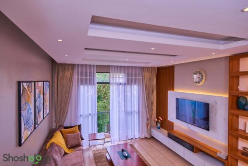 a living room with a tv and a large window at Shosholoza Homes in Wakiso