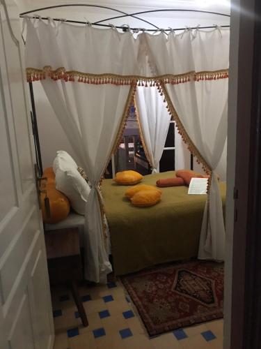 a bedroom with a canopy bed with orange pillows at Hôtel Riad Gnaoua in Essaouira