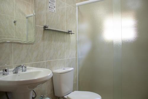 y baño con aseo, lavabo y ducha. en Pousada Vale Verde, en Campos do Jordão