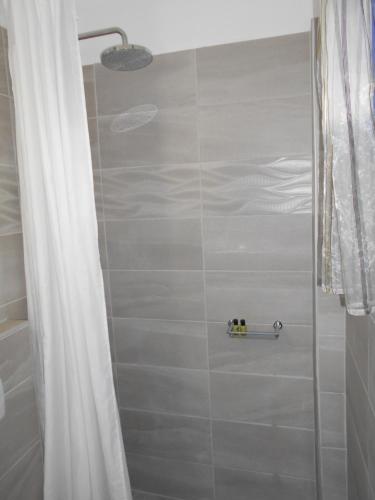 a bathroom with a shower with a white shower curtain at The Three Anchors Rooms in Emboríon