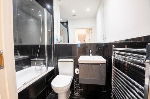 Baño en blanco y negro con aseo y lavamanos en Homely Entire Apartment - Long Stay, Contractors - Central Location, en Croydon