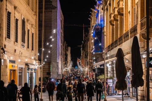 a crowd of people walking down a city street at night at Florette Suite Designer Finish with Stunning Lounge Terrace by ArcoBnb in Il-Furjana