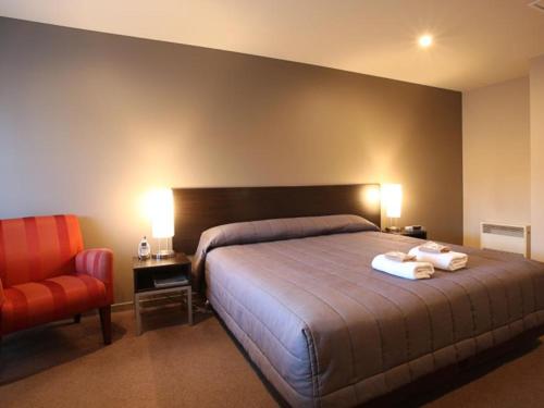 1 dormitorio con 1 cama y 1 silla roja en 388 Tay Motel en Invercargill