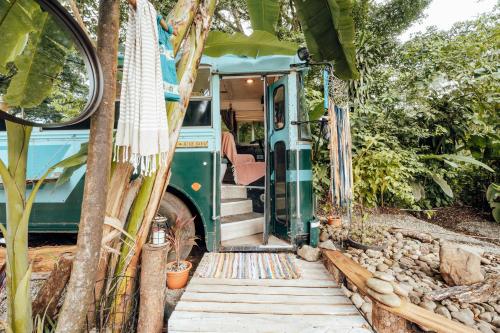 a green bus with its door open in a garden at Tribe Boutique Hotel - Adults Only in Dominical